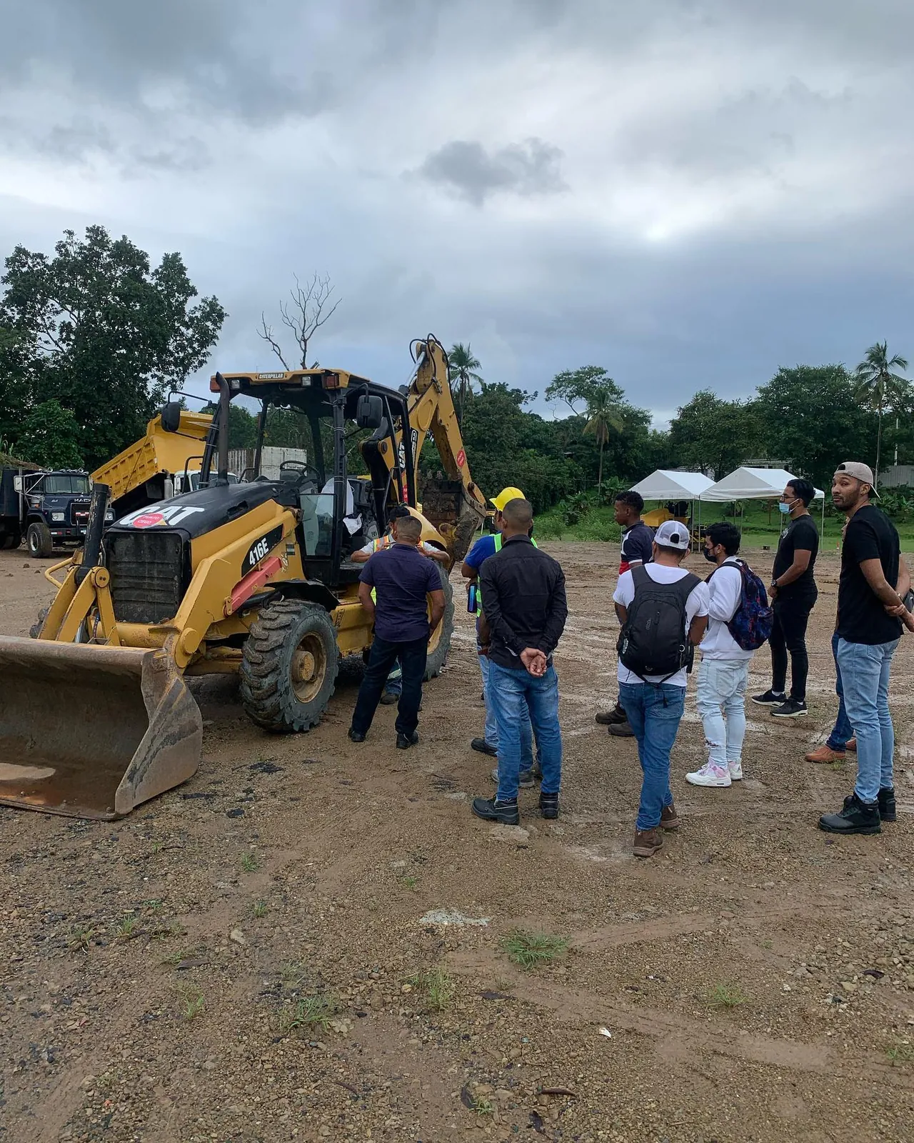 Grupo de personas junto a una retroexcavadora Caterpillar 416E durante una inducción.