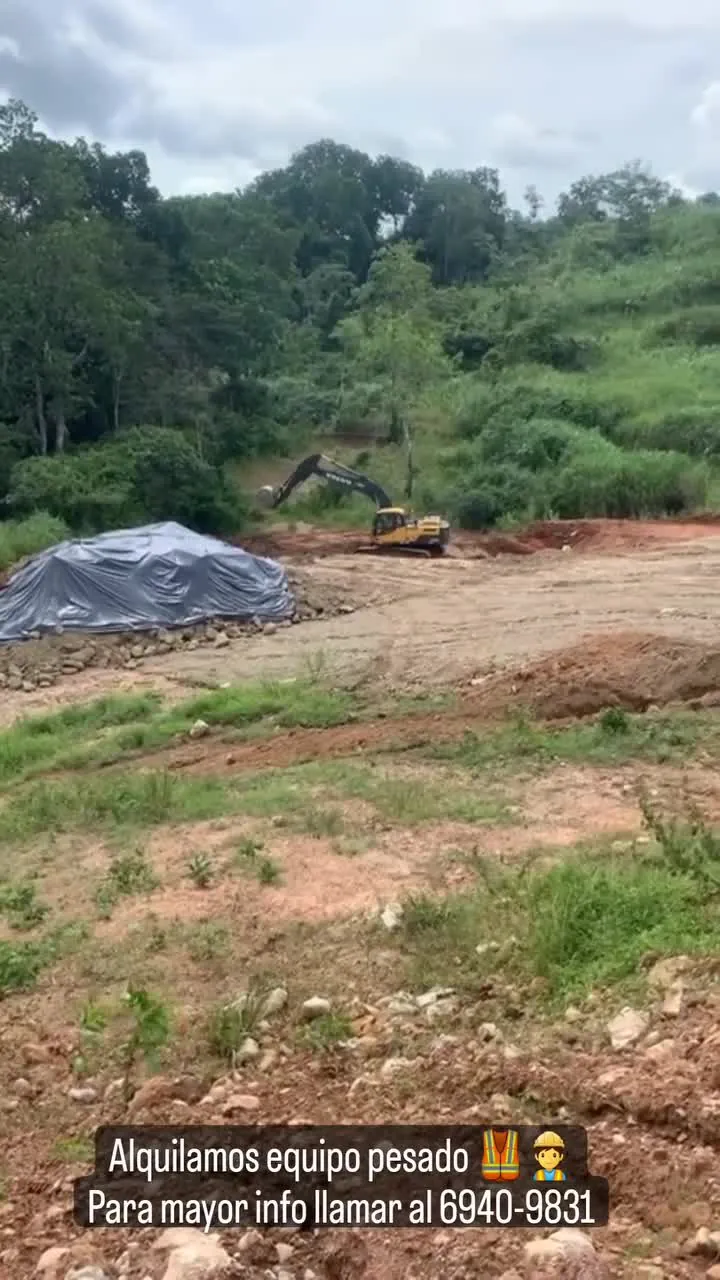 Excavadora trabajando un terreno abierto, con un letrero que invita a llamar al 6940-9831.